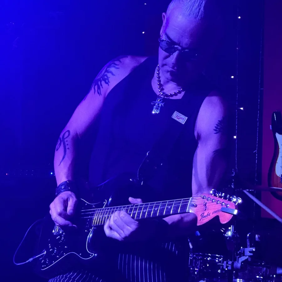 Rik Avalos playing guitar in blue stage light