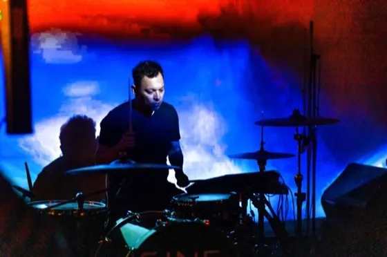 Sonny Sanchez behind the kit in blue stage light